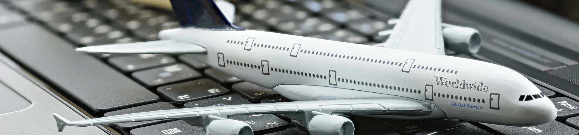 Aviation Management Diploma model airplane lands on a laptop keyboard with boxes of goods behind