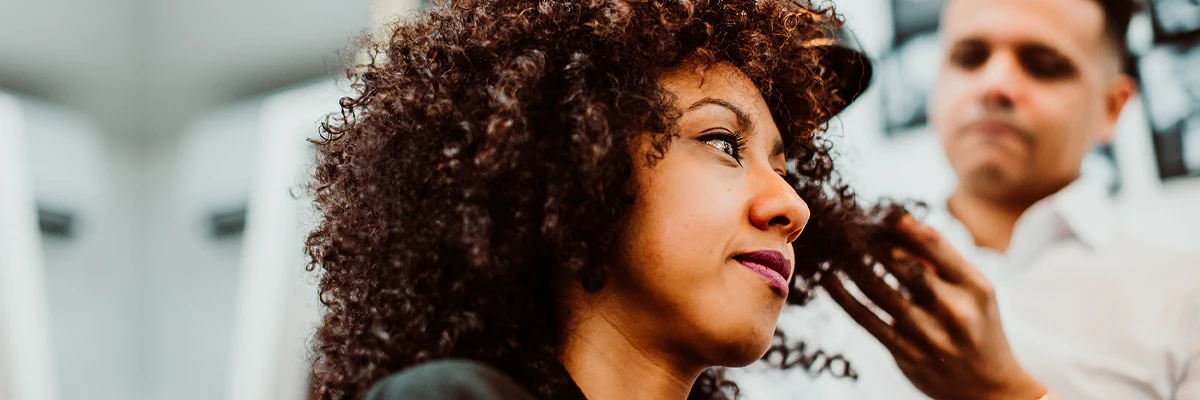 latin woman with short curly brown hair getting a treat at the hairdresser